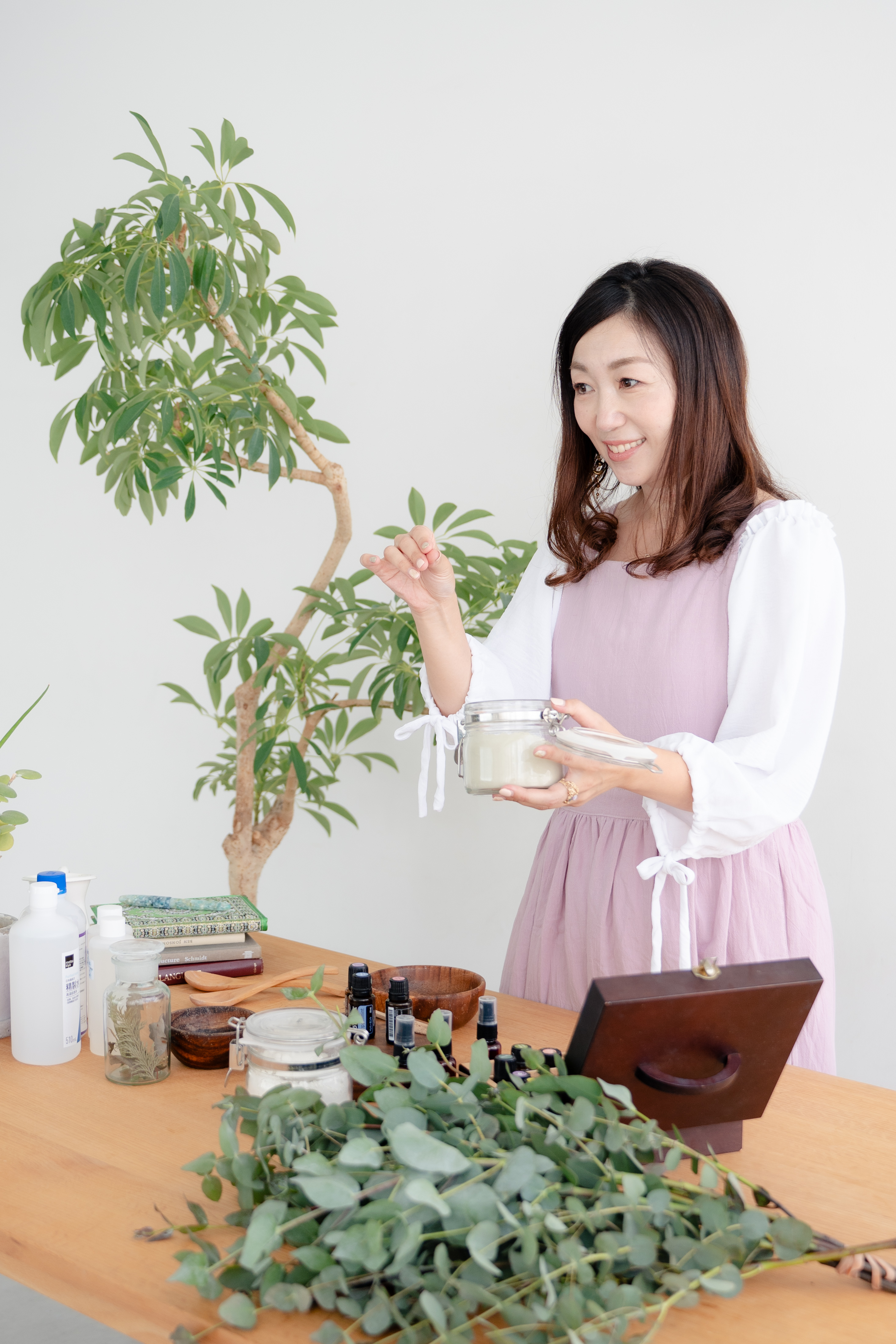 植物のそばでクレイの瓶を手に説明する千葉志織