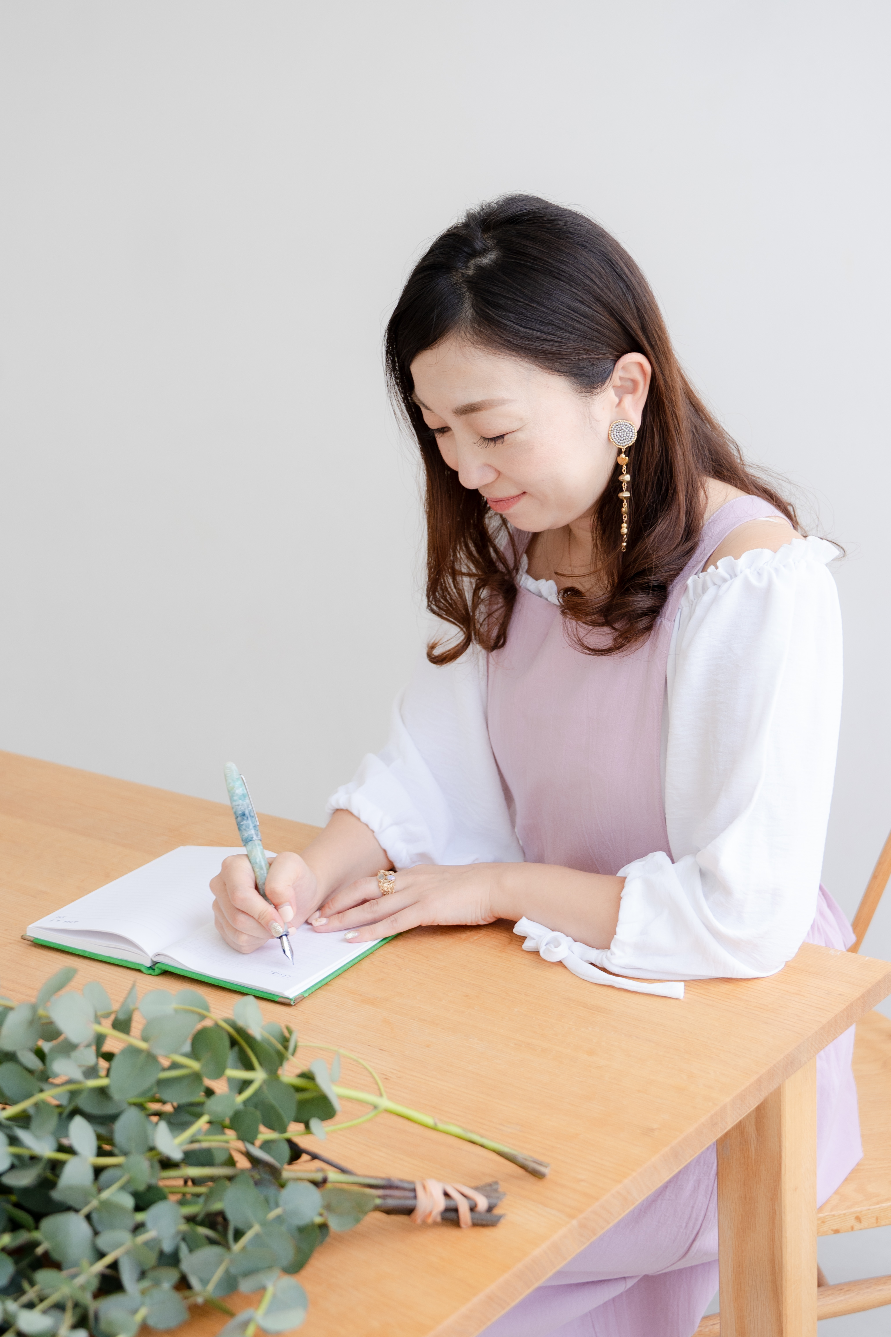 ノートに言葉を綴る手元と植物